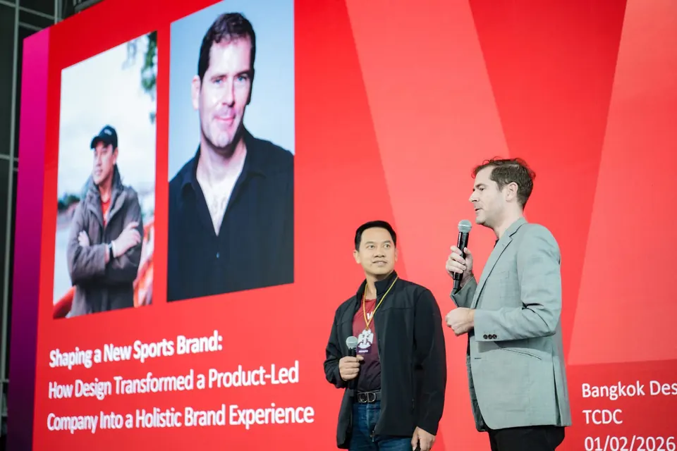 Sébastien and Watee Wichiennit on stage at TCDC, microphones in hand, under a slide reading Shaping a New Sports Brand.