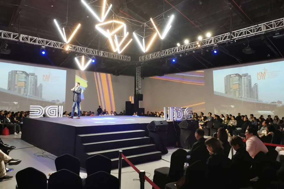 A wide view of the conference hall in Manila, with Sébastien speaking on stage under hanging light sculptures.