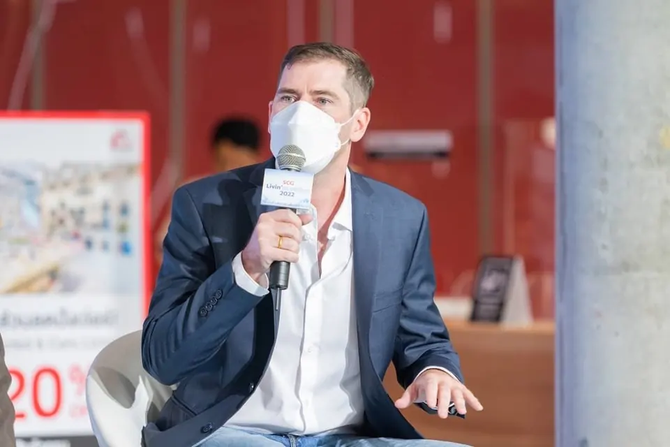 Sébastien, in a face mask, speaking into a microphone on a talk stage.