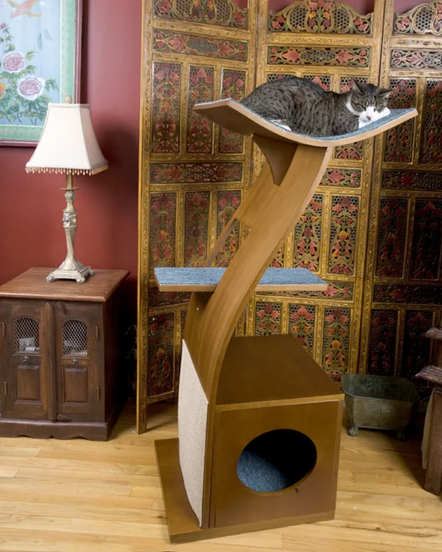 The Little Lotus cat tree at home: a curved wooden column rising from a box base, with a tabby cat asleep on its top platform.