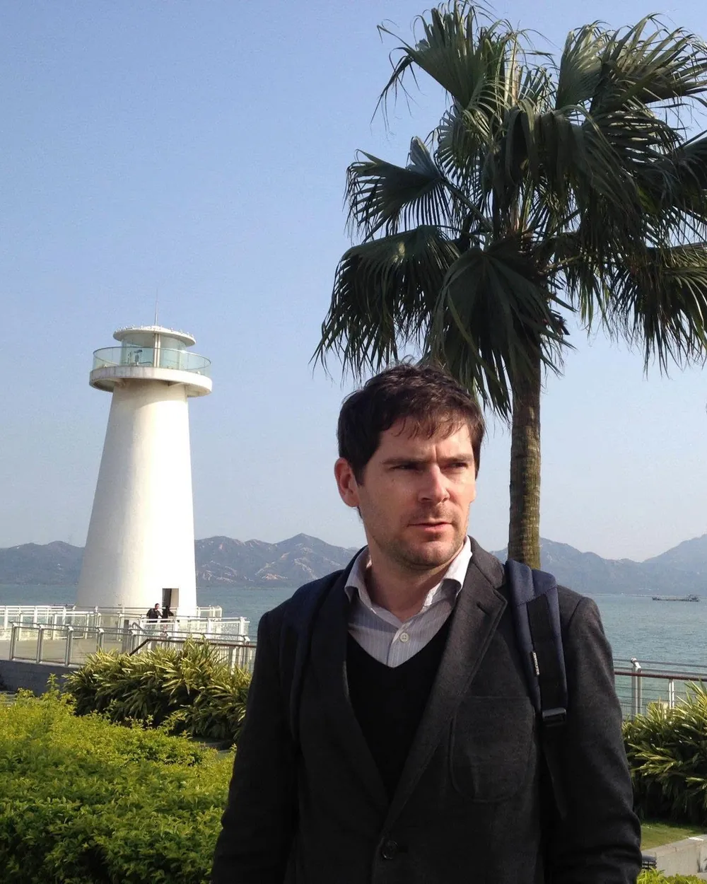 Sébastien on the Shenzhen seafront, by a white lighthouse and a palm tree, 2013.